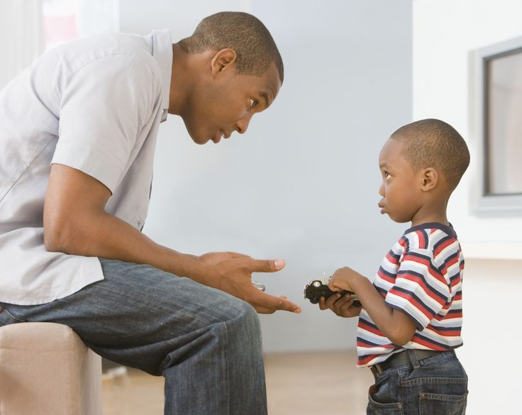 a man kneeling down next to a little boy who is holding something in his hand