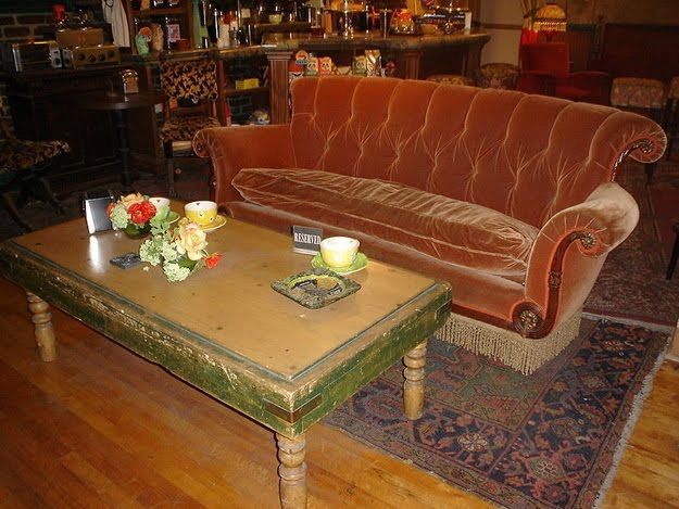 a couch and table in a room with many bottles on the shelves behind it,