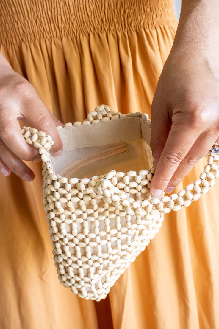 a woman is holding a purse made out of beads