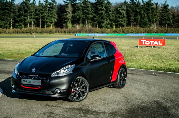 a small black and red car parked on the side of a road next to a field