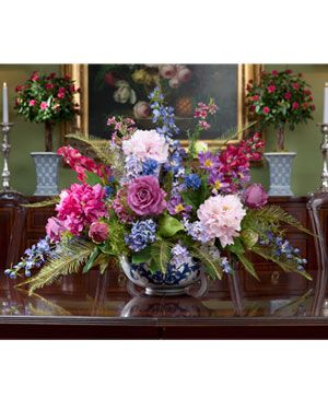 a vase filled with lots of flowers on top of a wooden table next to candles