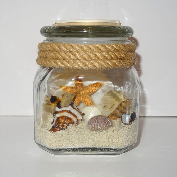 a glass jar filled with sand and shells