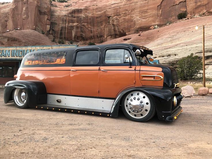 an orange and black truck parked in front of a mountain with rocks on the side