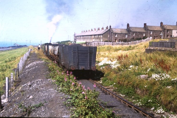 an old train traveling down tracks next to a rural area with houses in the background