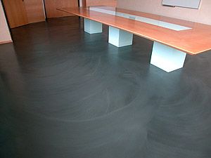 an empty conference room with black floor and wooden table in the center, surrounded by white pedestals