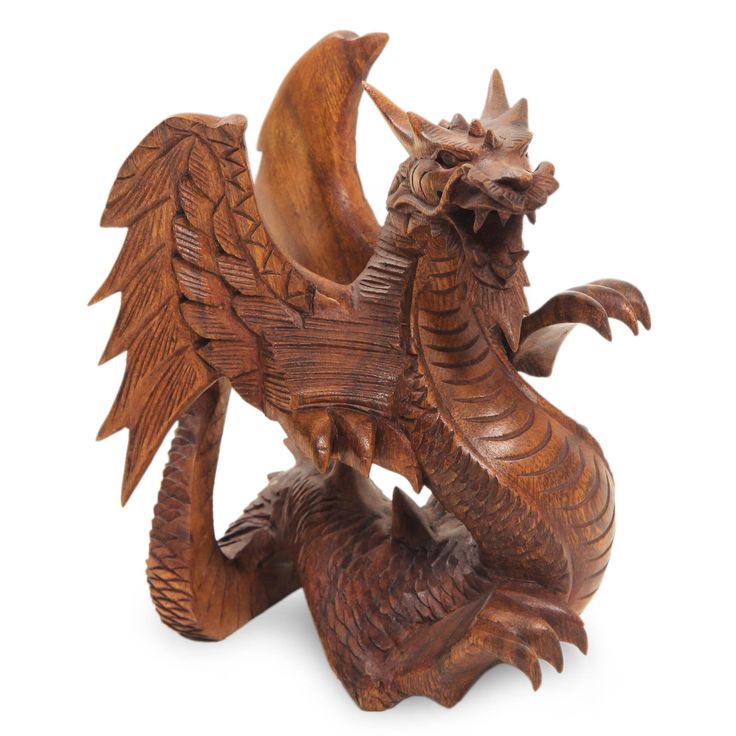 a wooden dragon statue sitting on top of a white surface