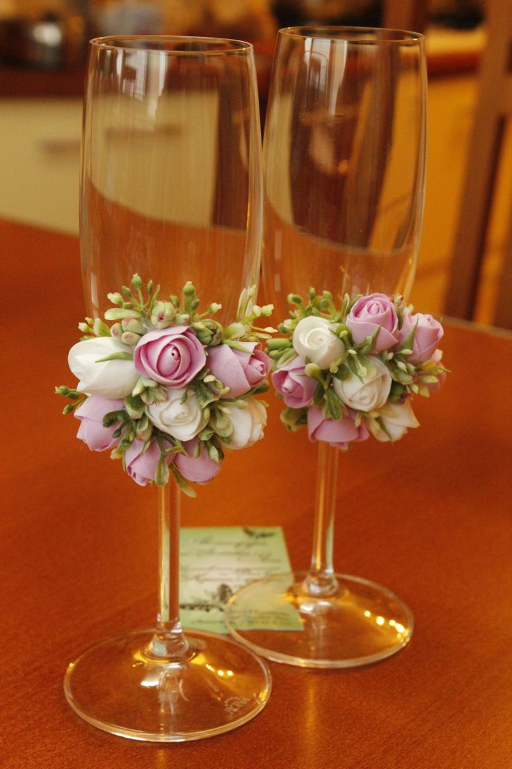 two wine glasses with flowers in them sitting on a table