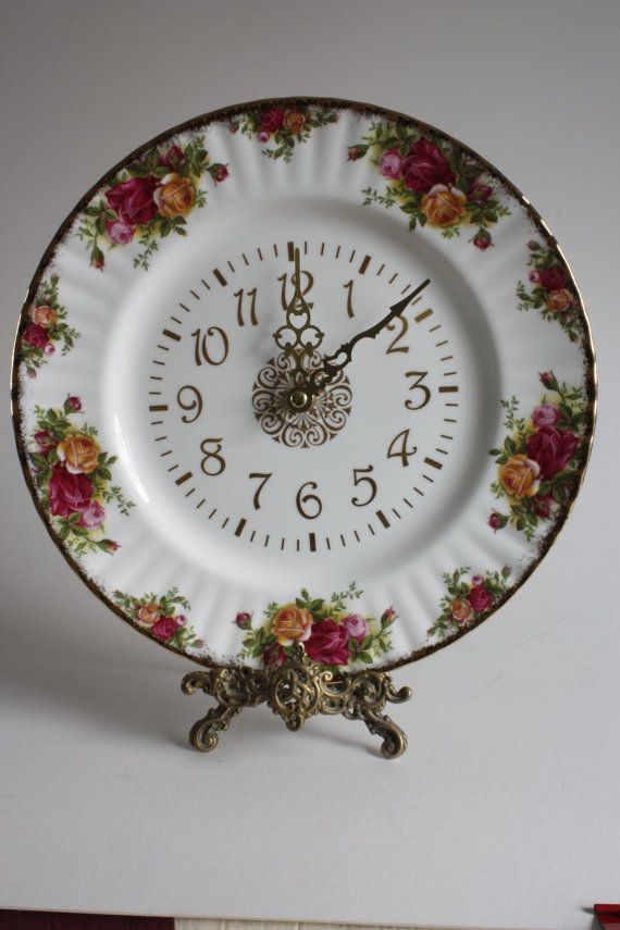 a white clock with flowers on it sitting on top of a table