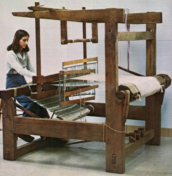 a woman is weaving fabric on an old loom with a machine in the background