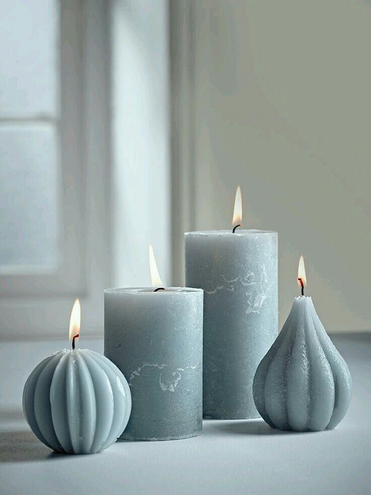 three white candles sitting next to each other in front of a window on a table