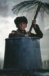 a man sitting in a bucket holding an umbrella