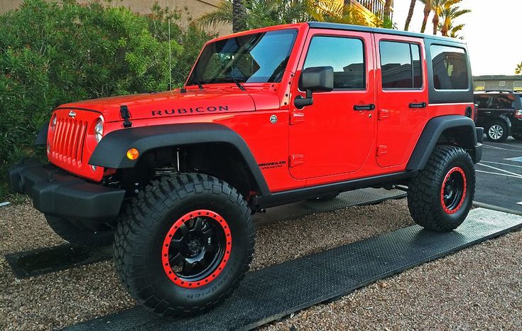 a red jeep is parked in a parking lot