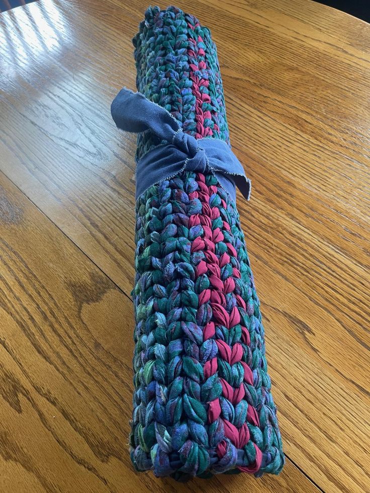 a roll of yarn sitting on top of a wooden table next to a blue ribbon