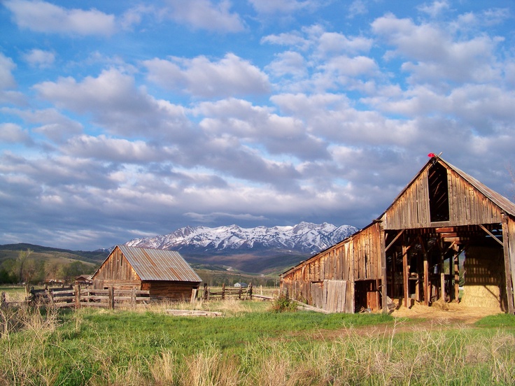 an old barn with mountains in the background