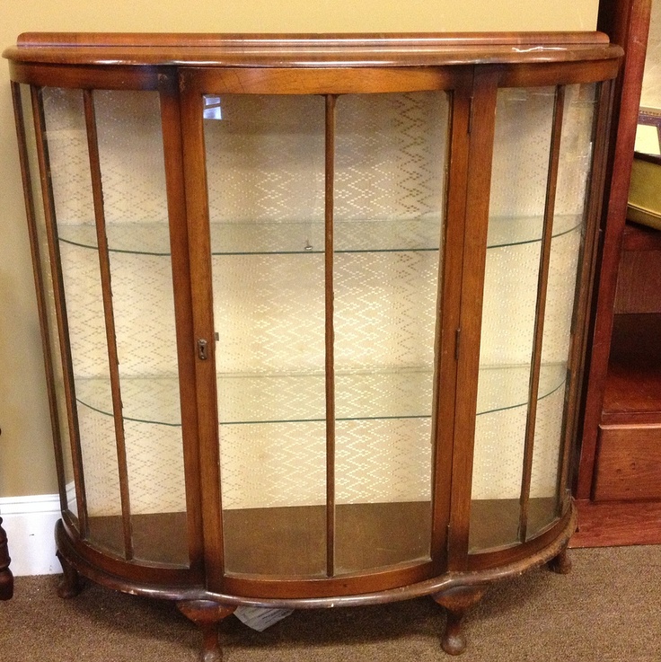 a wooden display case with glass doors on the top and bottom shelves, in front of a brown carpeted floor