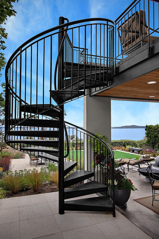 there is a spiral staircase going up to the top floor in this modern home with outdoor dining area