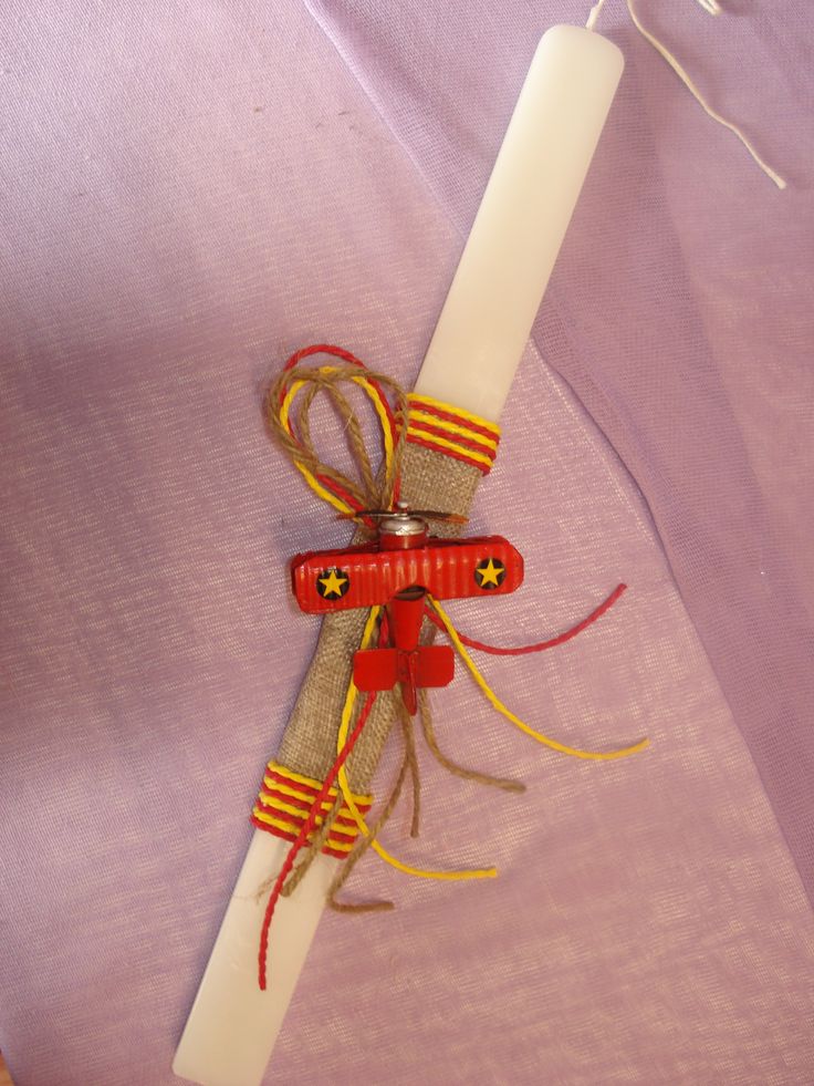 a white candle is wrapped in twine and tied with red, yellow, and orange ribbon