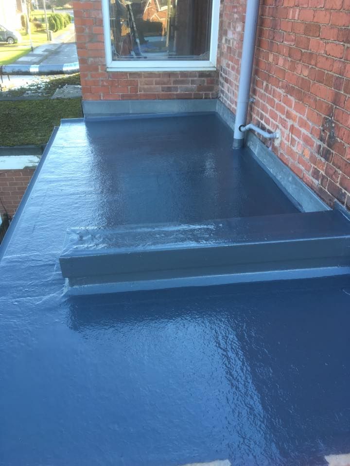 a blue flat surface on the side of a brick building with a window in it