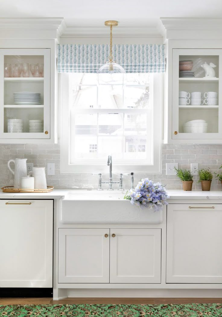 a kitchen with white cabinets and blue flowers on the counter top, along with a green area rug