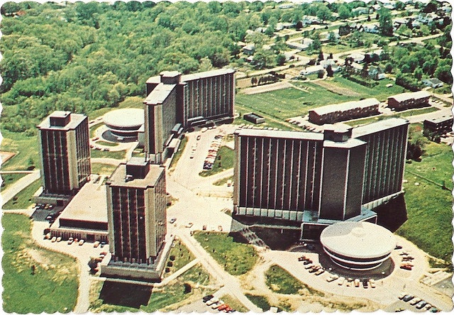 an aerial view of some buildings in the middle of a green area with trees around it