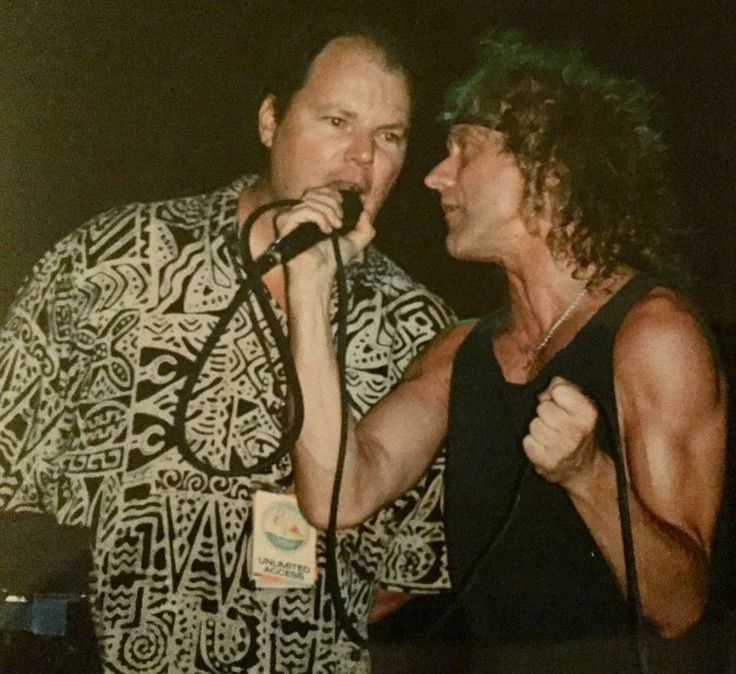 two men standing next to each other with microphones in their hands and one man singing into the microphone