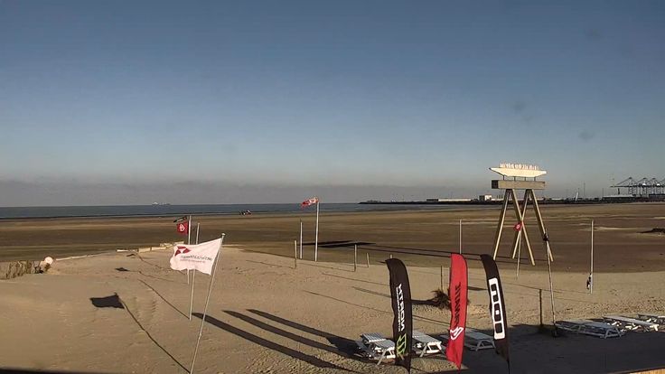 an empty beach with flags and signs on it