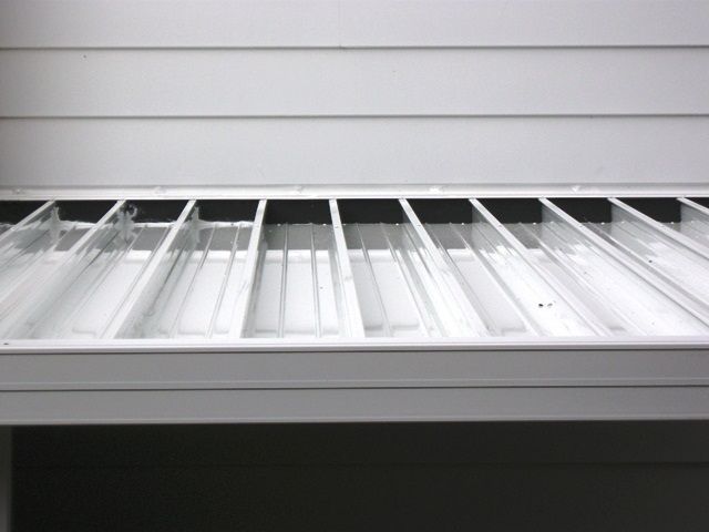 the bottom shelf of a white refrigerator with no ice cubes on it's sides