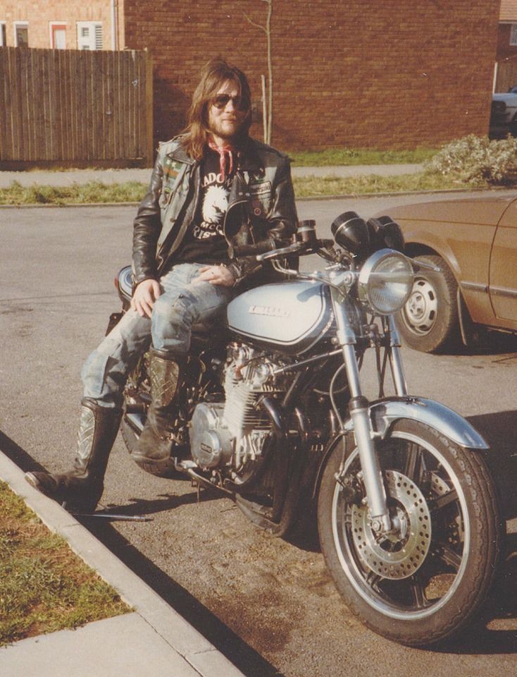 a man is sitting on his motorcycle in the parking lot