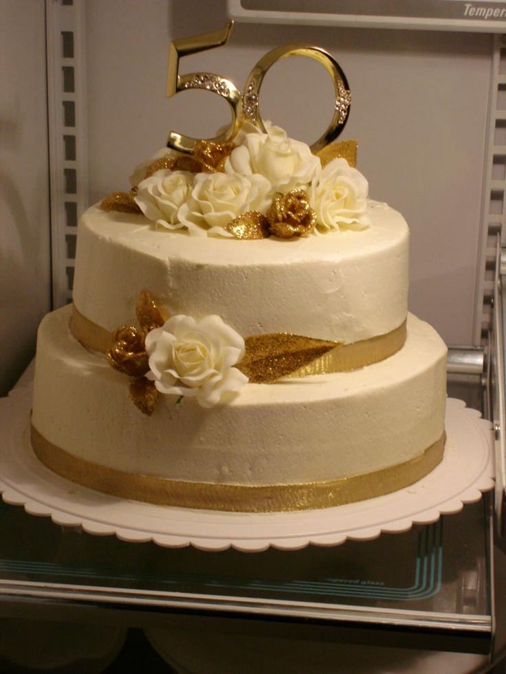 a white cake with gold decoration and flowers