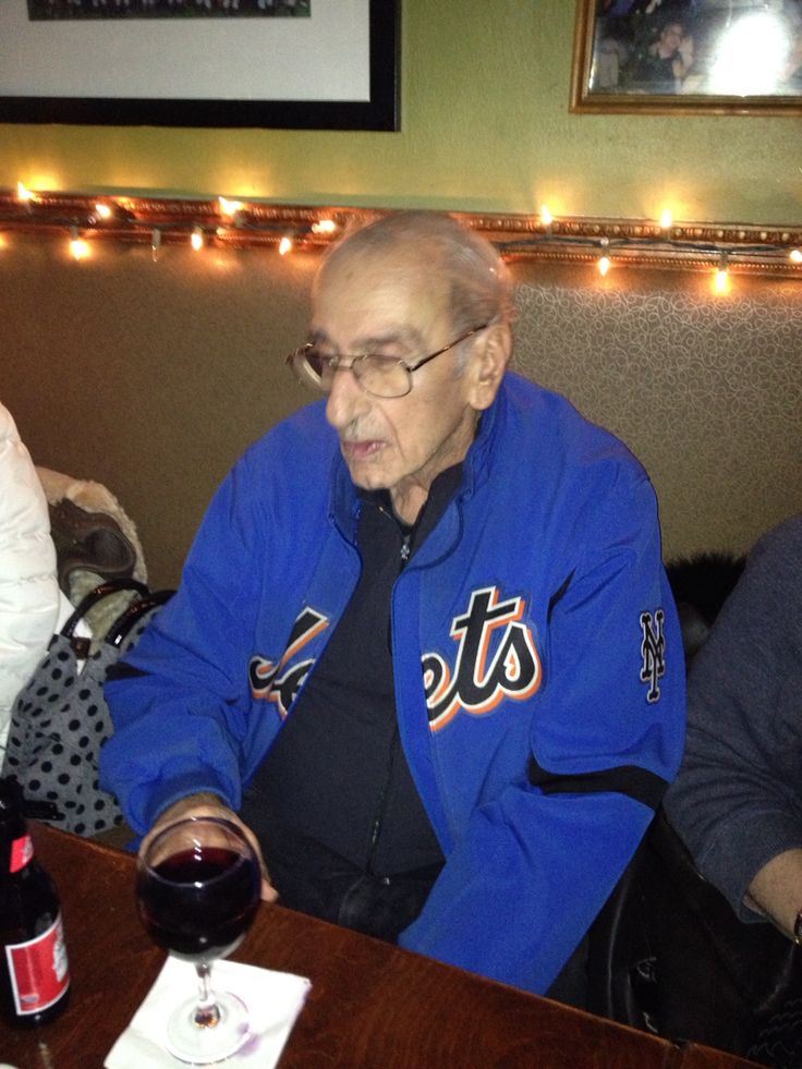 an old man sitting at a table with a glass of wine