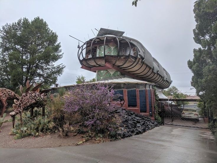 an unusual house in the middle of trees and bushes