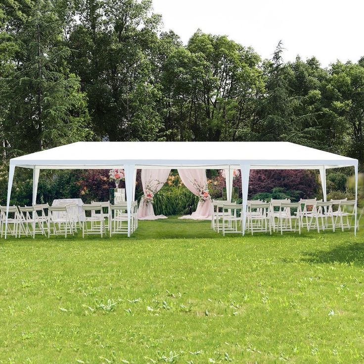 a large white tent set up in the middle of a field with chairs around it