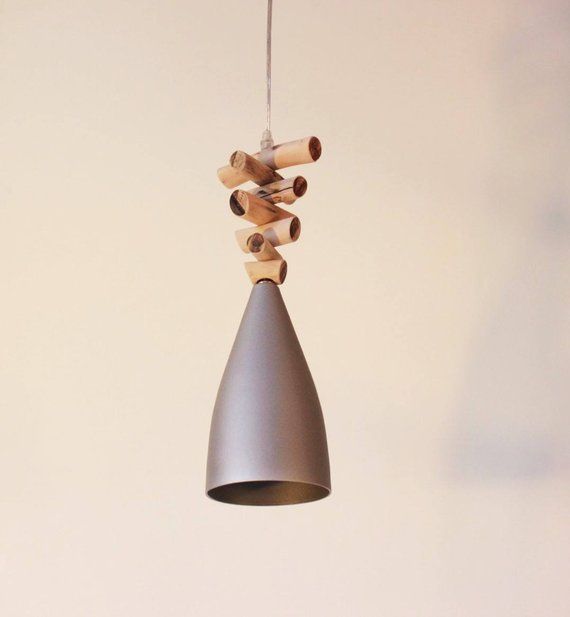 a gray light hanging from a string with wooden dows attached to the end and a white wall in the background