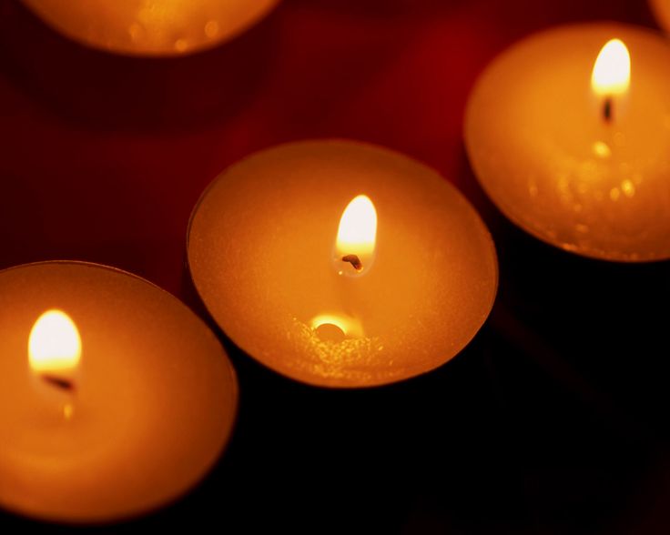 several lit candles are arranged in rows on a table