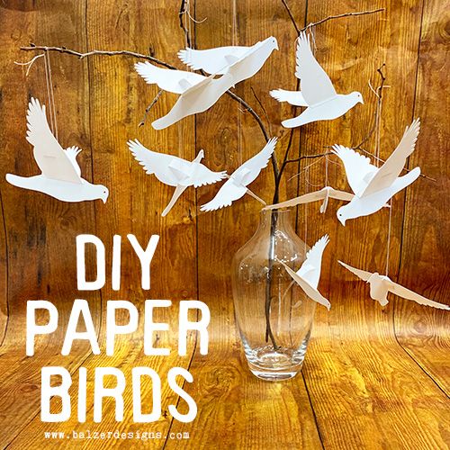 a vase filled with paper birds sitting on top of a wooden table