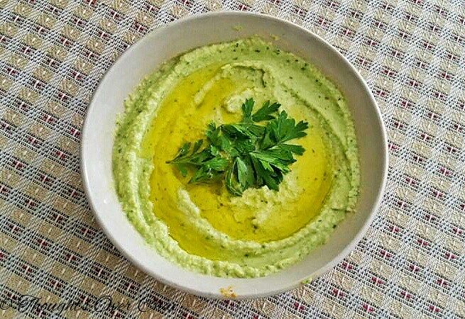 a white bowl filled with guacamole and garnished with parsley