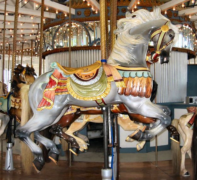 an old fashioned merry go round with horses on it's sides and lights hanging from the ceiling