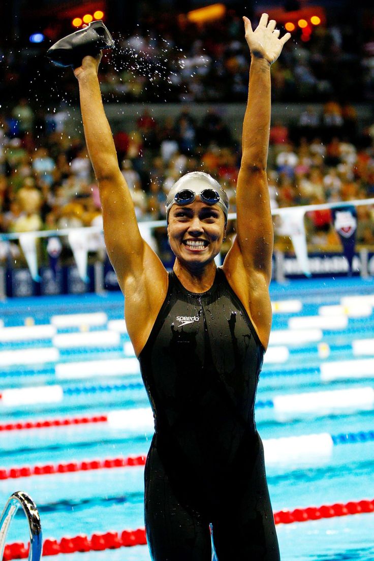 a woman standing on top of a swimming pool holding her hands up in the air