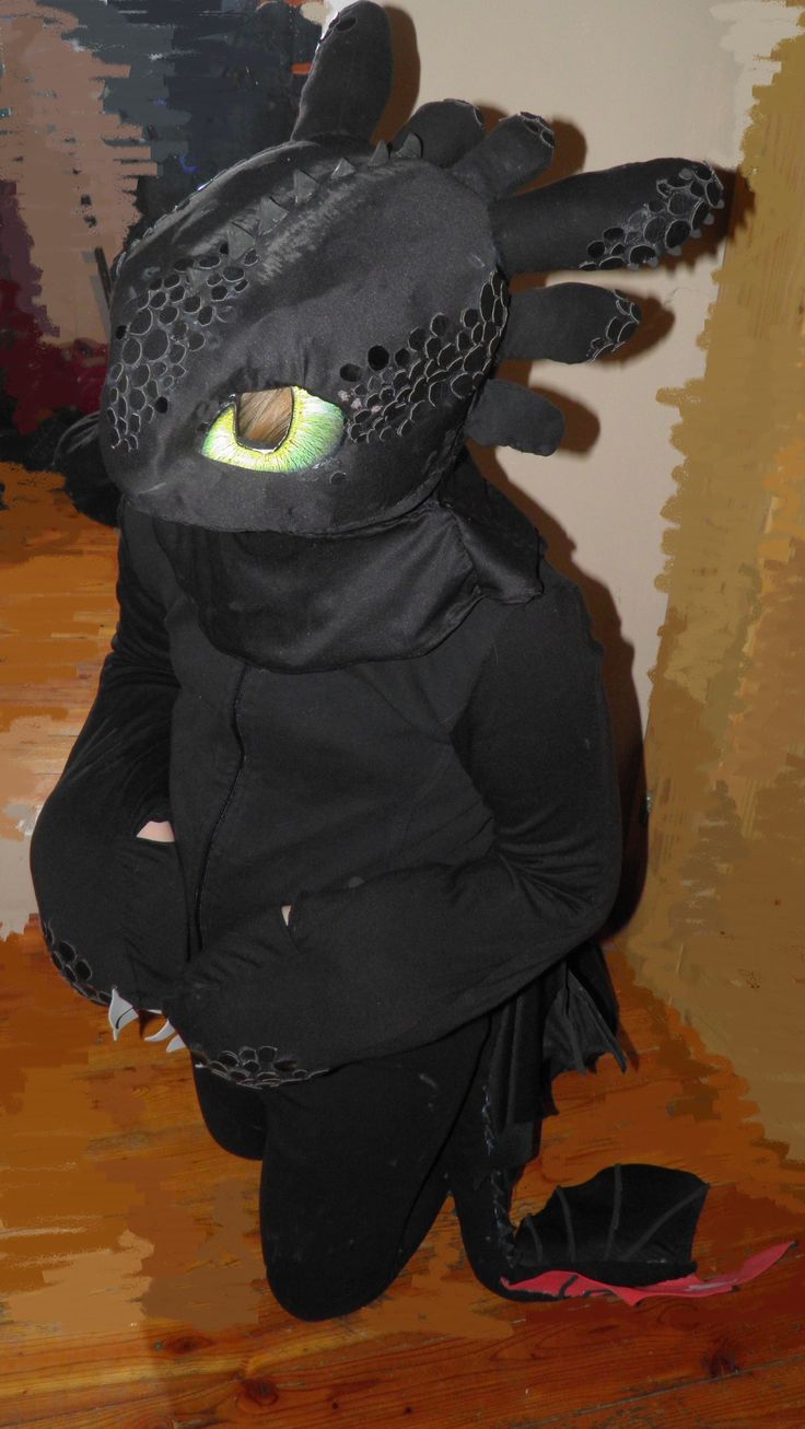 a person in a dragon costume sitting on the floor with their hands behind their back