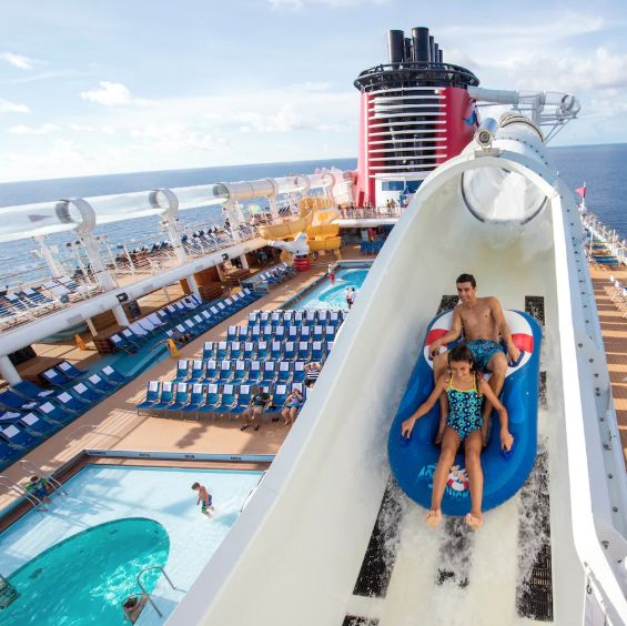 two people are riding on a water slide in the middle of a cruise ship pool