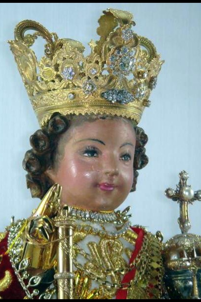 a doll wearing a gold crown and holding a cross