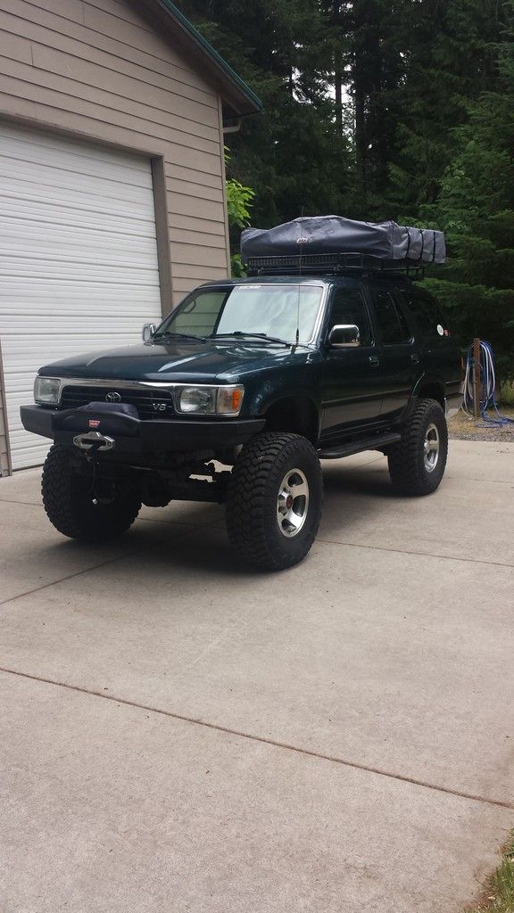 a black truck parked in front of a garage with a camper on it's roof