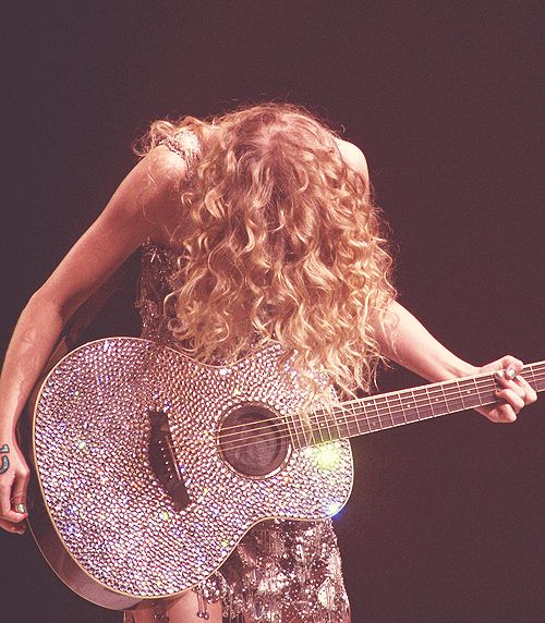 a woman with curly hair holding a guitar