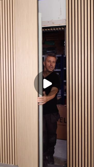 a man standing in front of a wooden wall with vertical slats on the walls