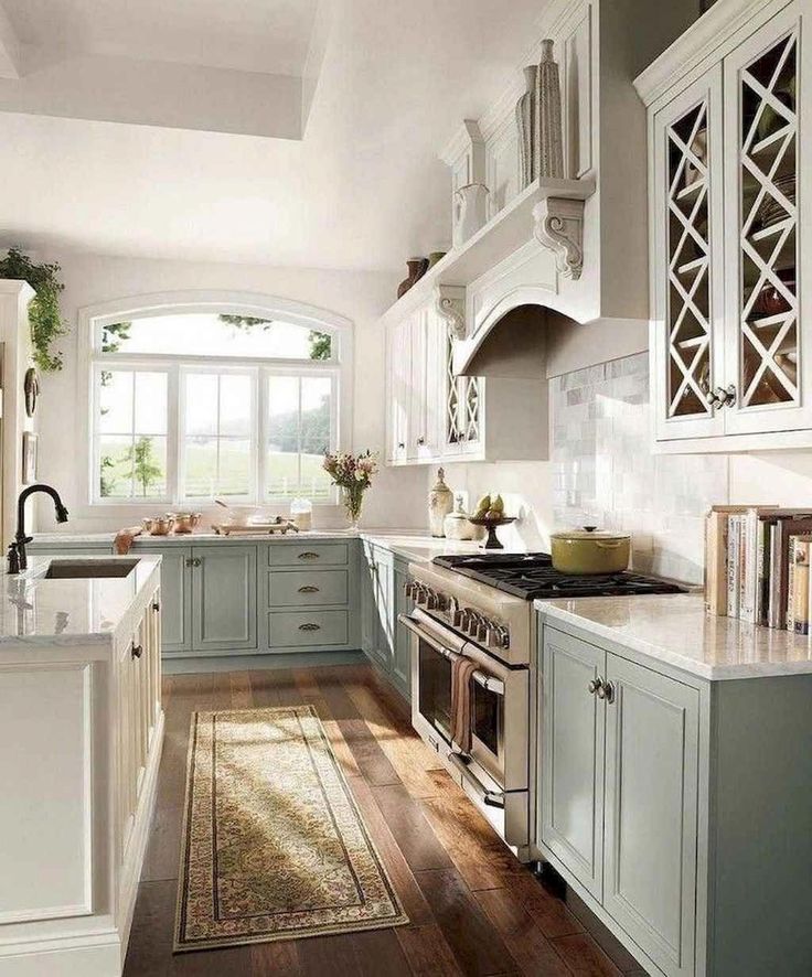 a kitchen filled with lots of white cabinets and wooden flooring next to a stove top oven