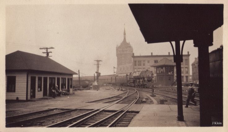 an old black and white photo of train tracks in front of a building with a clock tower