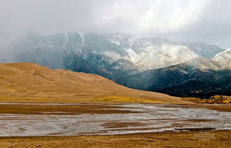 the mountains are covered in snow and brown grass