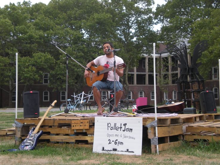 a man sitting on top of a wooden pallet with a guitar in front of him