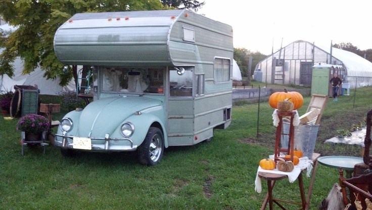 an old camper is parked in the grass with pumpkins and other things on it