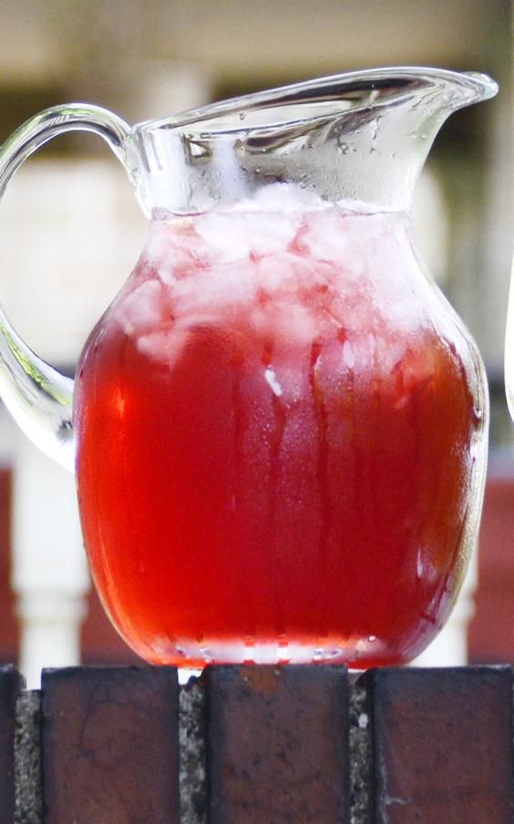 a pitcher filled with liquid sitting on top of a brick wall